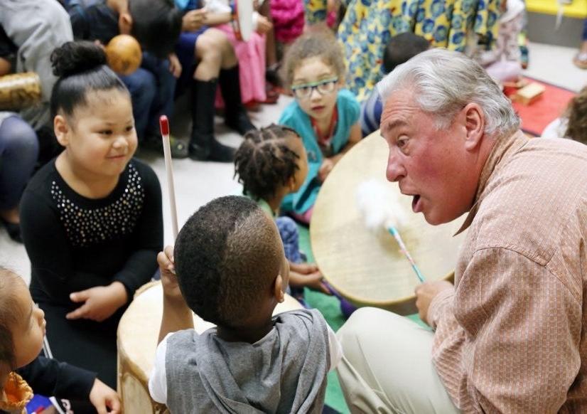 Teaching artist drumming with 3 elementary children