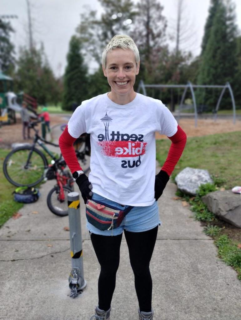 volunteer standing at park wearing "Seattle Bike Bus" t-shirt